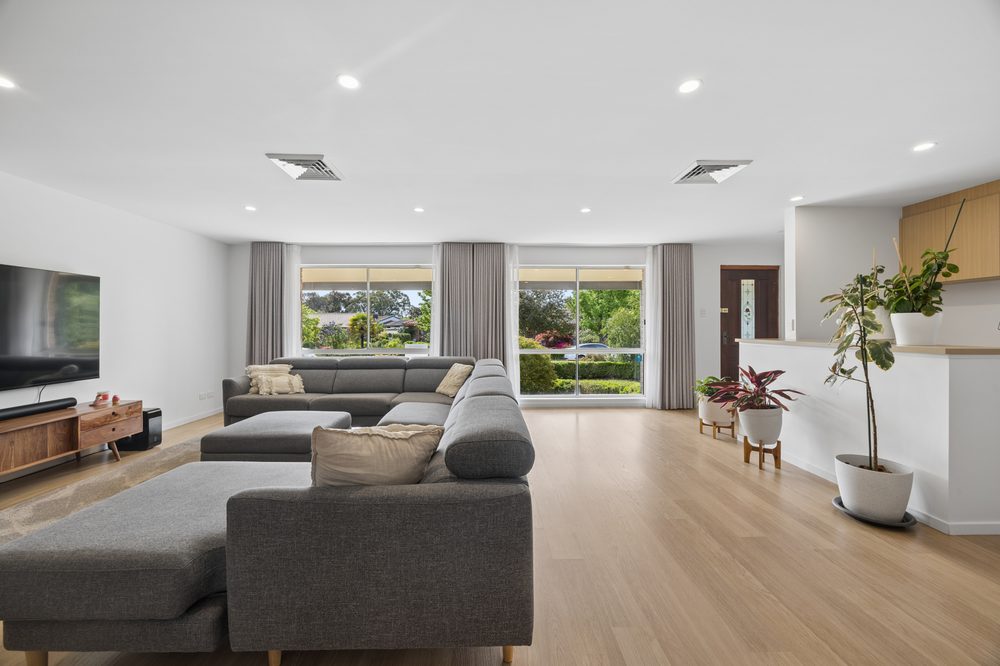 Large living room with a grey sofa, timber floors and windows to the garden
